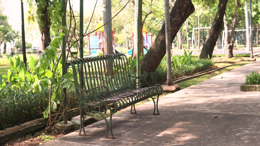 Empty bench of Asian playground in the summer during pandemic. Quite ambience with windy weather in the park. Conceptual footage for impact of coronavirus. Medium shot of empty bench.