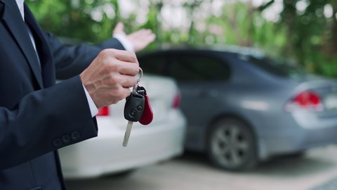 A car dealer is showing a key to use in the test drive. The seller sends car keys to the renter for use in traveling. Concept Selling and renting cars.