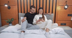 Young couple sits on the sofa in the living room, female playing game on a smartphone, girl wins the game, emotions of victory, self-isolation.
