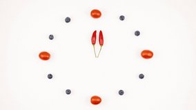 Creative concept of a clock made of tomatoes, blueberries and chillies.  Stop motion animation, on white background, clockwise and anticlockwise.  Space for text.