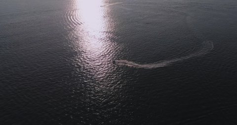 Water motorcycle is moving on the surface of sea on beautiful sunset. Aerial view, drone shot. Travel vacation, water sports, active leisure concept