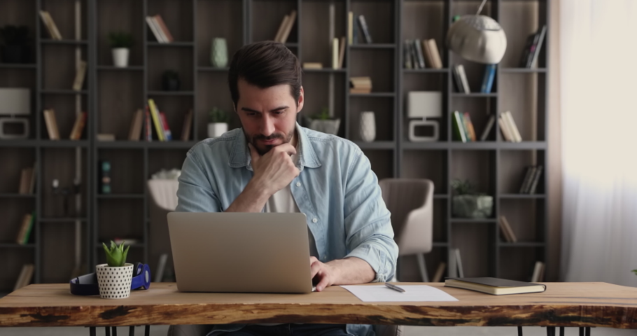 Satisfied freelancer working using laptop thinking, ponder on creative telecommute task. Confident business man sitting at workplace office desk smile makes task successfully, enjoy fruitful workday | Shutterstock HD Video #1065744370