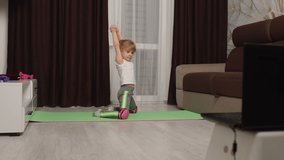Fit little girl kid doing gymnastics stretching workout at home, watching online lessons on laptop pc. Child pupil online video distance sport exercises education during coronavirus covid-19 lockdown