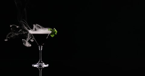Glass of liquid nitrogen cocktail on black background