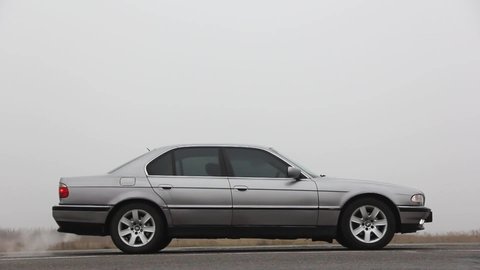Chernigov, Ukraine - January 6, 2021: Car with headlights on. Old car BMW 7 Series (E38) on the road against a background of fog. Gloomy weather. 