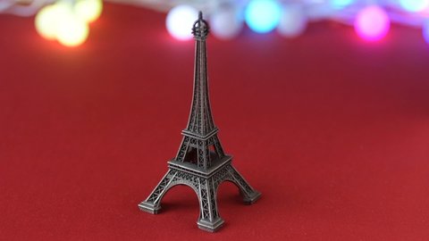 Eiffel tower statuette colourful lights garland background red heart shaped sugar confetti fall down scatter. France, romantic love, Valentine's Day preparation design concept