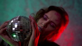 merry disco party, woman is viewing mirror ball, holding it in hands - Powered by Shutterstock - Get 15% off with code: PIKWIZARD15