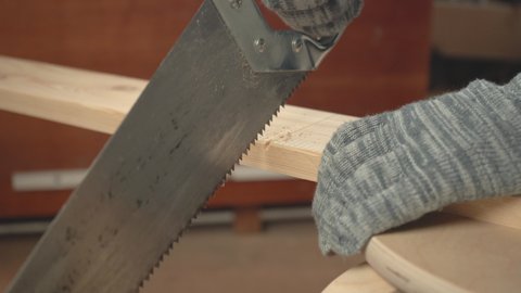 Man hand saws a board with an old hacksaw