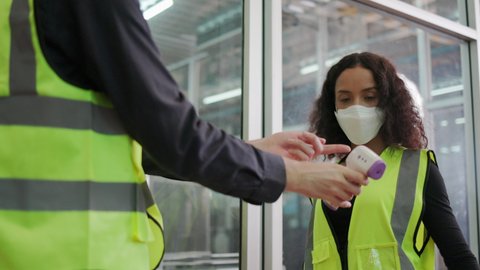Construction worker put on face mask and Face Shield used body temperature monitor on factory Staff. Prevent COVID-19 Coronavirus and Dust PM2.5 In the industrial plant. Concept Health care