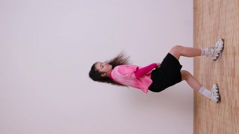 Vertical video for social media. Young woman dancing moves. The girl is dancing in shorts and a T-shirt, in the studio.