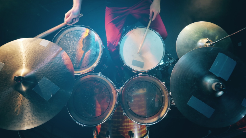 View from above on the drums and cymbals during playing. Drum set, drum kit in dark, drummer plays a concert.