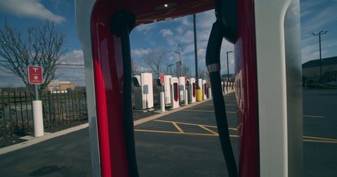 Staten Island, New York  United States - January 17,  2021: Tesla electric car Supercharger power station in strip mall parking lot.  Close up Tesla logo on Supercharger.