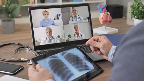doctor having a work group video chat conference using computer,back view of male medic join an online meeting with colleagues to discuss and examine coronavirus lung x-ray disease on laptop screen