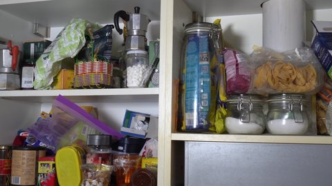 clutter in the house - kitchen cabinet full of messy objects and food - young people live alone during Covid-19 Coronavirus lockdown quarantine - need to do cleaning in the apartment and kitchen