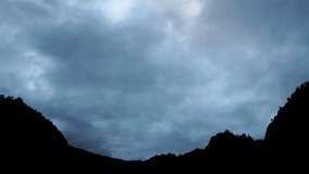 High-speed shooting of a landscape in the mountains. Thick beautiful clouds fly over the tops of the black mountains. Timelapse, 4k video.