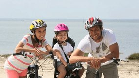Portrait of happy family riding bikes on a sandy path