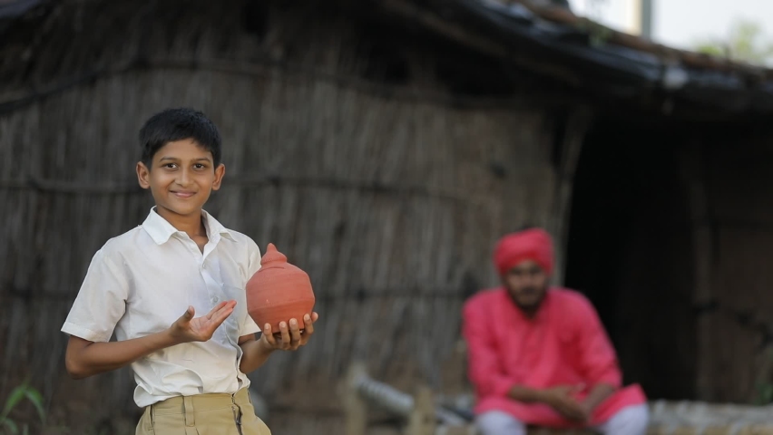 Poor farmer child holding clay piggy bank in hand with farmer at home