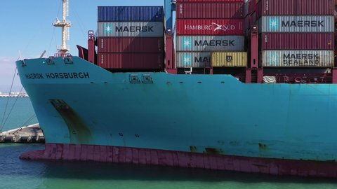 Haifa, Israel - November 1, 2020: Maersk Mega Container Ship loaded to the top with Shipping Containers, anchored at port, low aerial pass.
