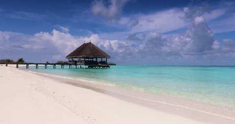 A tropical beach in the Maldives islands with turquoise sea, sandy beach and a water lodge over the ocean