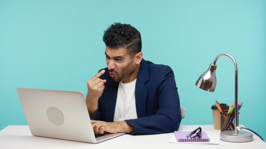You are liar! Extremely angry annoyed man screaming blaming and accusing of lying his interlocutor having video call on laptop. Indoor studio shot isolated on blue background | Shutterstock HD Video #1065813226