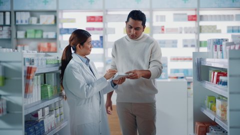 Pharmacy Drugstore: Female Asian Pharmacist Helping Indian Male Customer with Recommendation, and Advice to Buy Medicine, Drugs, Vitamins. Modern Pharma Store Shelves with Health Care Products