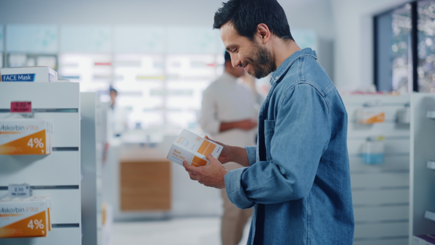 Pharmacy Drugstore: Portrait of Handsome Latin Man Choosing to Buy Medicine Browsing through the Shelf, Successfully finds Package that he Needs, Smiles Happily. Pharma Store Health Care Products | Shutterstock HD Video #1065814342