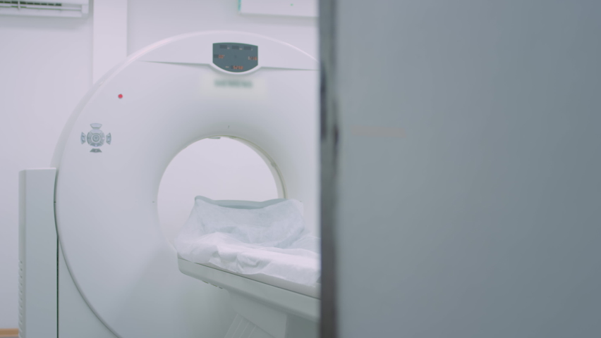 A patient in a medical mask is lying at a modern computer tomography machine. The doctor analyzes the lungs on a CT scanner. The danger of covid or coronavirus. Examining the organ of the lungs Royalty-Free Stock Footage #1065825328