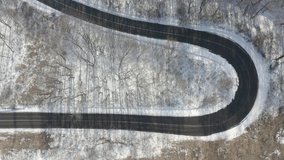 Snowy winter serpentines forest with little traffic on the road on the hill. Aerial 4K view in Visegrad, Hungary. RAW footage for creators to color grade  