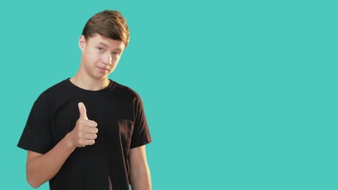 Like gesture. Ok sign. Good job. Right choice. Information banner. Encourage idea. Teenager boy black t-shirt showing supporting hand pointing copy space isolated turquoise. Advertising background.