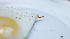 Fried chicken egg, shape in the form of a heart. Fried egg seasoned with salt and pepper. Food for Valentine's Day. Concept of a funny surprise for a loved one for a special ocasion. 4K video. Macro