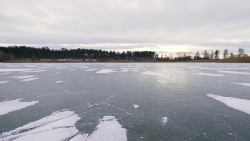 A young and beautiful woman is skating on ice. The lake froze over and turned into a natural ice rink.
