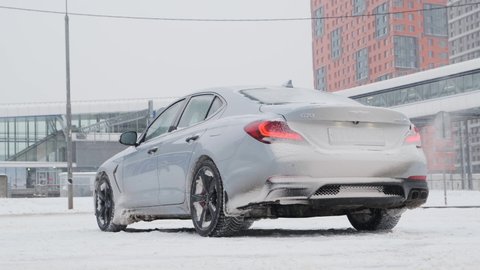 Moscow, Russia - CIRCA 2020: New car model Genesis G70 gray-blue on the road. Dolly shot of back of the car.