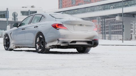 Moscow, Russia - CIRCA 2020: New car model Genesis G70 gray-blue on the road. View from back. Camra spin around back of automobile.