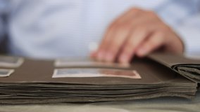 Man flips through the pages of an old album and looks through photographs. - Powered by Shutterstock - Get 15% off with code: PIKWIZARD15