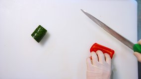 Chef hands slicing sweet red bell pepper on a white cutting board. Beautiful video with soft focus. Healthy food concept.