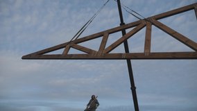 Construction work. Installation of a wooden truss on the roof of a private house. A worker directs the farm. - Powered by Shutterstock - Get 15% off with code: PIKWIZARD15