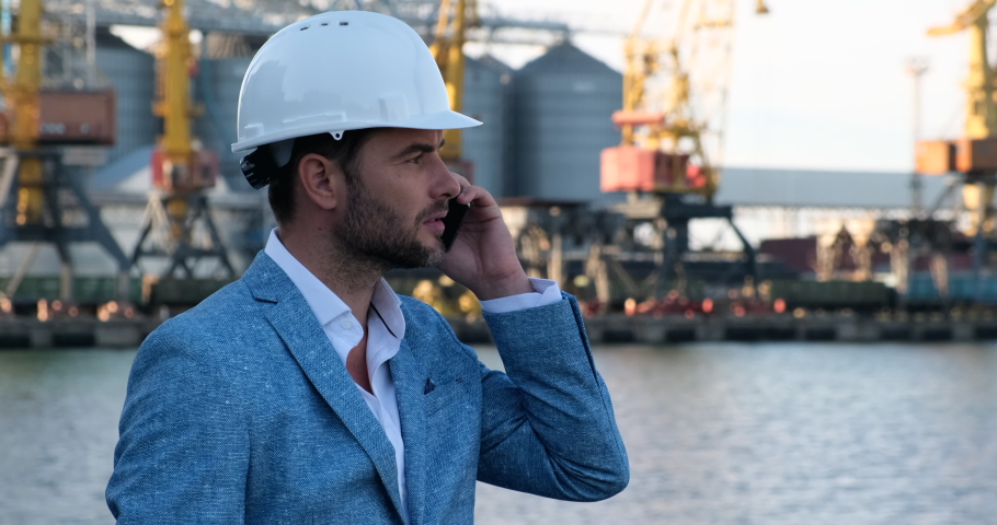 manager,workers, speaks on a mobile phone, in a protective helmet, in a business jacket, controls the loading of the ship, freight,sea Port .cargo delivery by sea, cargo ship, grain storage,ODESSA
