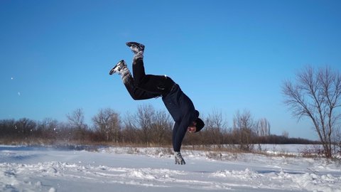 Happy Guy Stuntman Runs in the Snow and does Cool Trick Somersaults in the Snowdrift. Man is Having Fun in a Winter Glade in the Forest. Positive Emotions. Slow motion. High quality FullHD footage