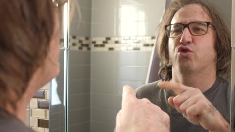 In front of the bathroom mirror, a man is giving himself a boost of confidence by doing a pep talk