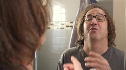 Man in front of a mirror in his bathroom giving a pep talk to motivate himself.
