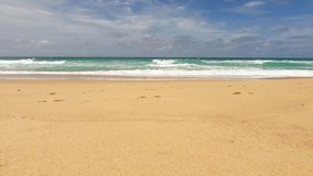 Landscape view of beautiful tropical summer sandy beach with deep blue sea water n ocean white foam wave crashing sand shore in sunlight sunshine day on cloud sky, 4k cinemagraphs b-roll footage video