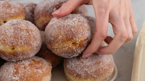 Berliners. Female hands lay donuts on a rectangular plate on a white background. Delicious sweet donuts. Making donuts with jam.