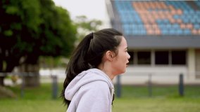 Asian woman is running on the stadium track in the evening after working.Running,Healthy lifestyle, workout and diet concept.