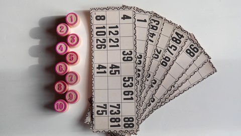 Traditional old Russian board game Russian Lotto. Cards with numbers, closeup. Red Wooden barrels with numbers lie on a table, on a white background.