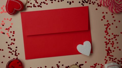 Valentine's day concept, female hands put a heart in a red envelope, pink background. February 14th. St. Valentine's Day