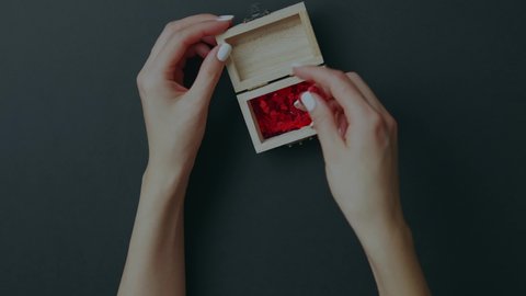Valentine's day concept, female hands transfer hearts from a wooden box, gray background. February 14th. St. Valentine's Day