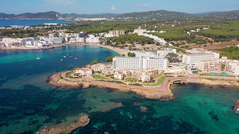 Aerial drone footage of the beautiful island of Ibiza, Spain in the Balearic islands showing the beach and hotels by the mediterranean sea and the beach of Playa Es Canar in the village of Es Canar