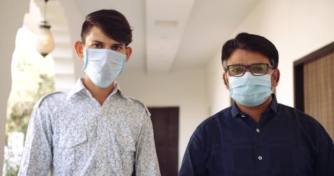 Slow-motion of two adult males wearing face mask standing in a hospital corridor hallway- raise their hand sin thumbs up sign hand gestures for best of luck wishes