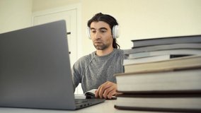 guy student wearing headphones using laptop for distance education, enjoying conference video call, watching webinar, listening audio course, writing notes, studying with teacher, having lesson