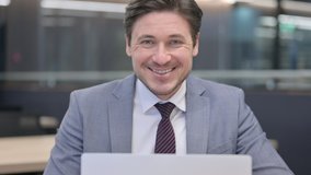 Close Up of Middle Aged Businessman with Laptop Smiling at Camera - Powered by Shutterstock - Get 15% off with code: PIKWIZARD15
